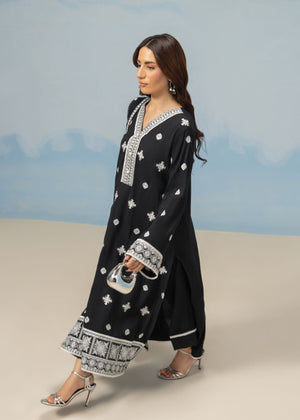 Women's 3-piece black winter suit, side view of long tunic with white motif trim