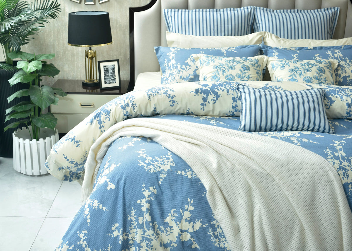 Light blue floral quilt cover with striped pillows and draped white underside on bed