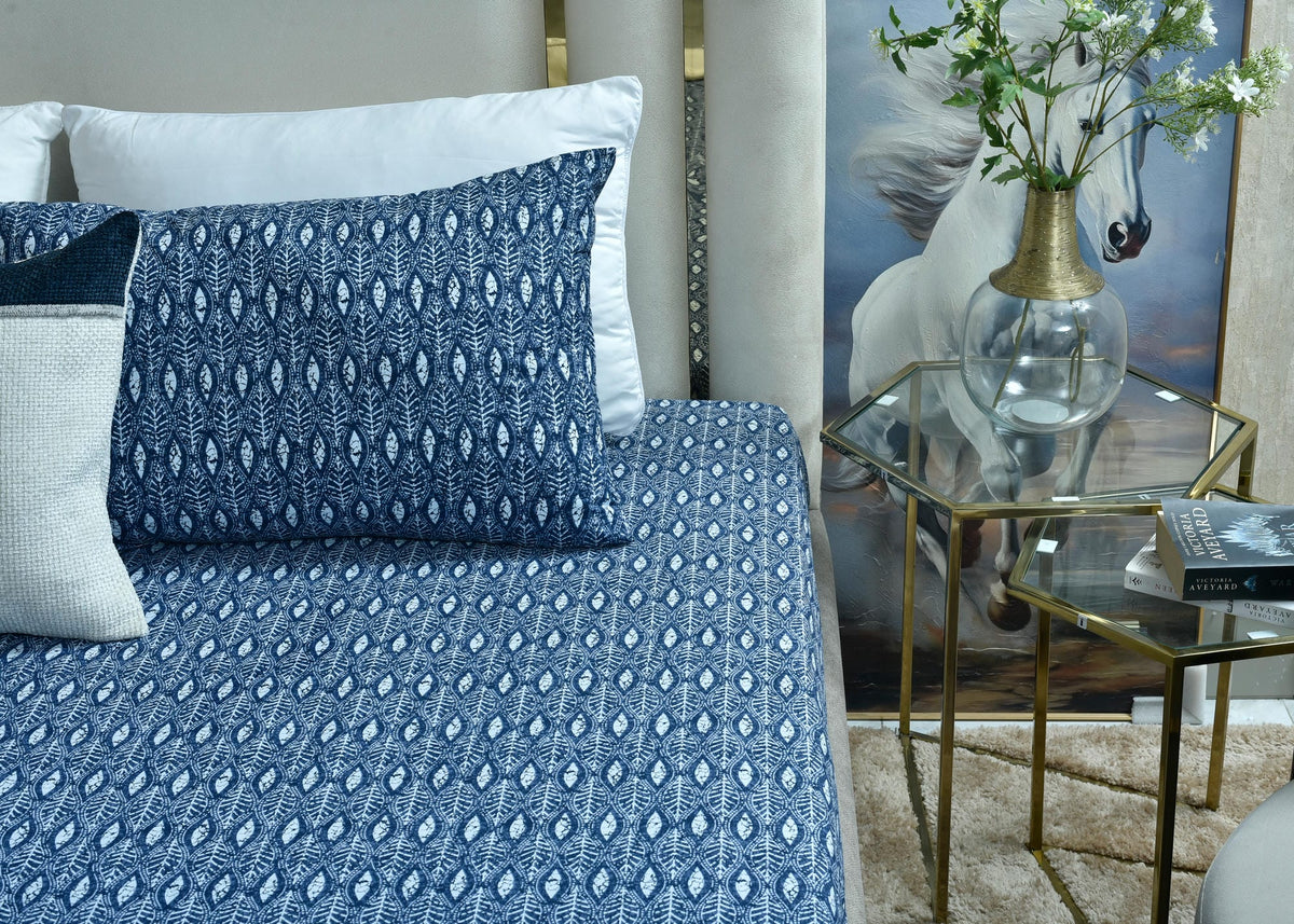 Blue patterned bed sheet with matching navy pillowcases and one light accent pillow