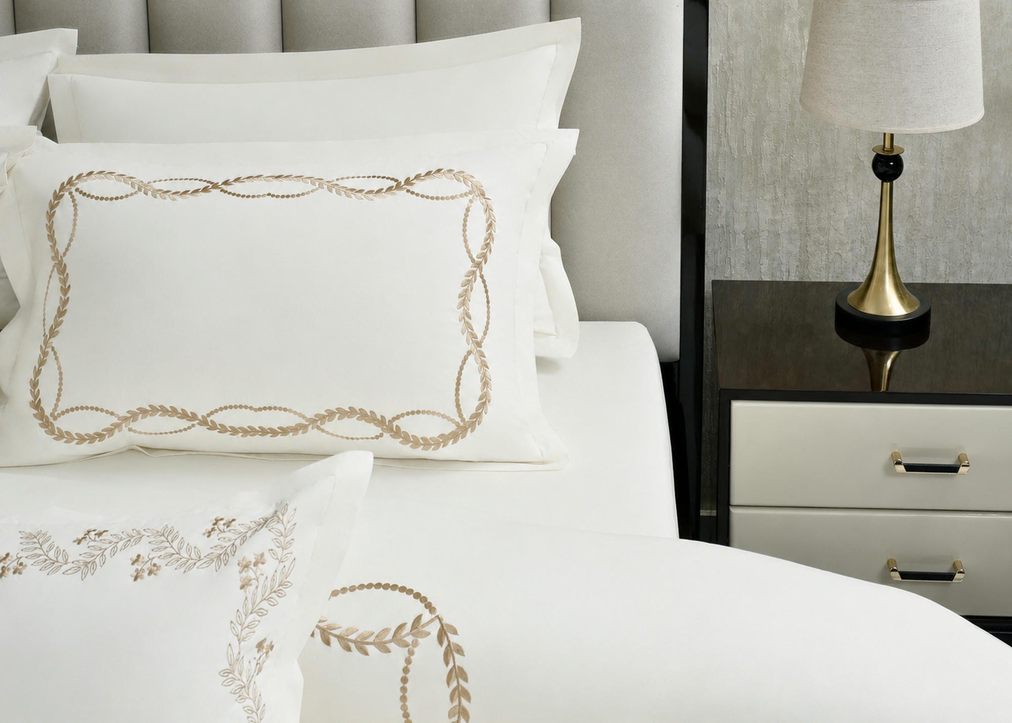 White pillow shams with gold loop border on a matching duvet cover set