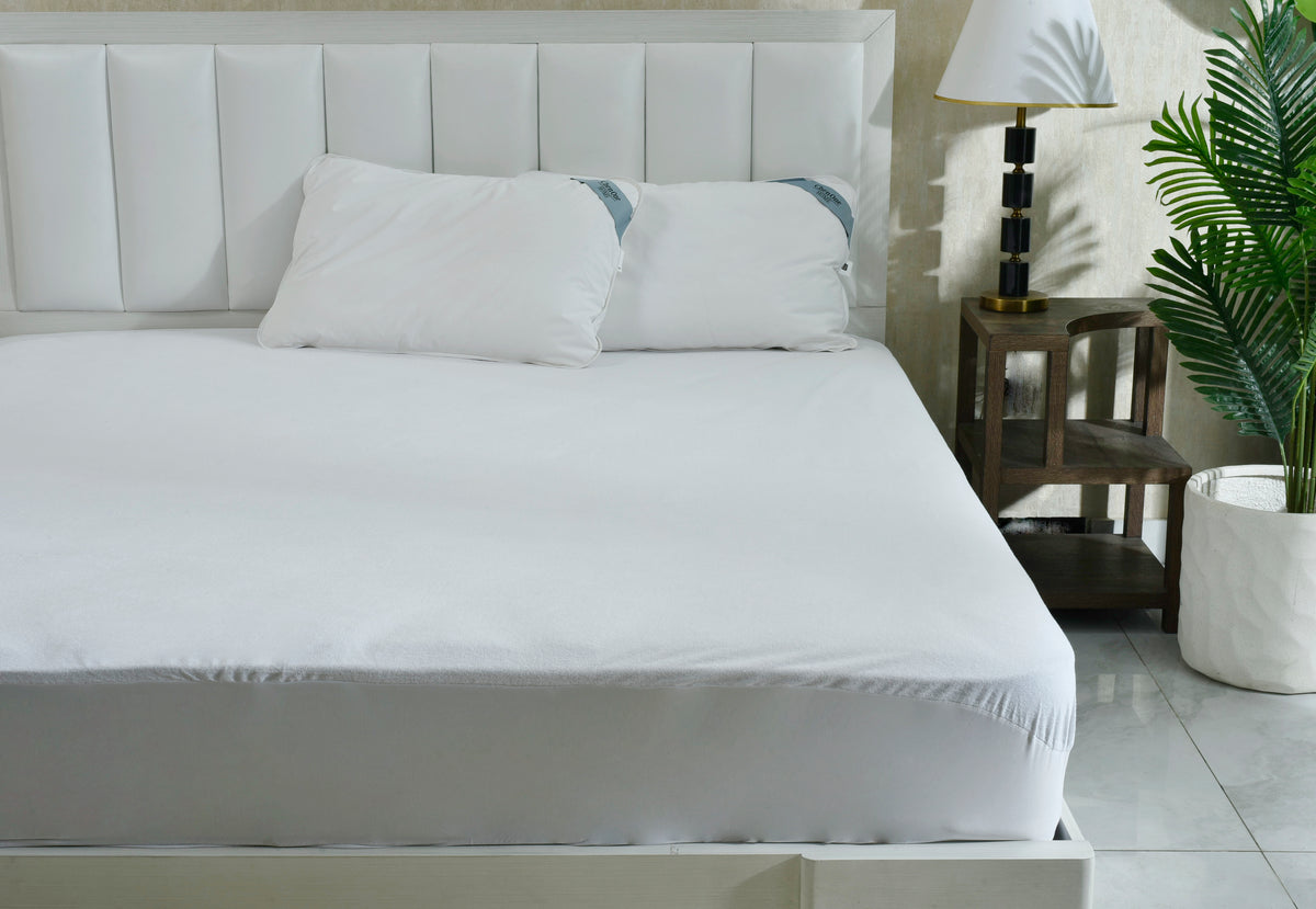 Terry mattress protector in white, fitted over bed mattress top and sides