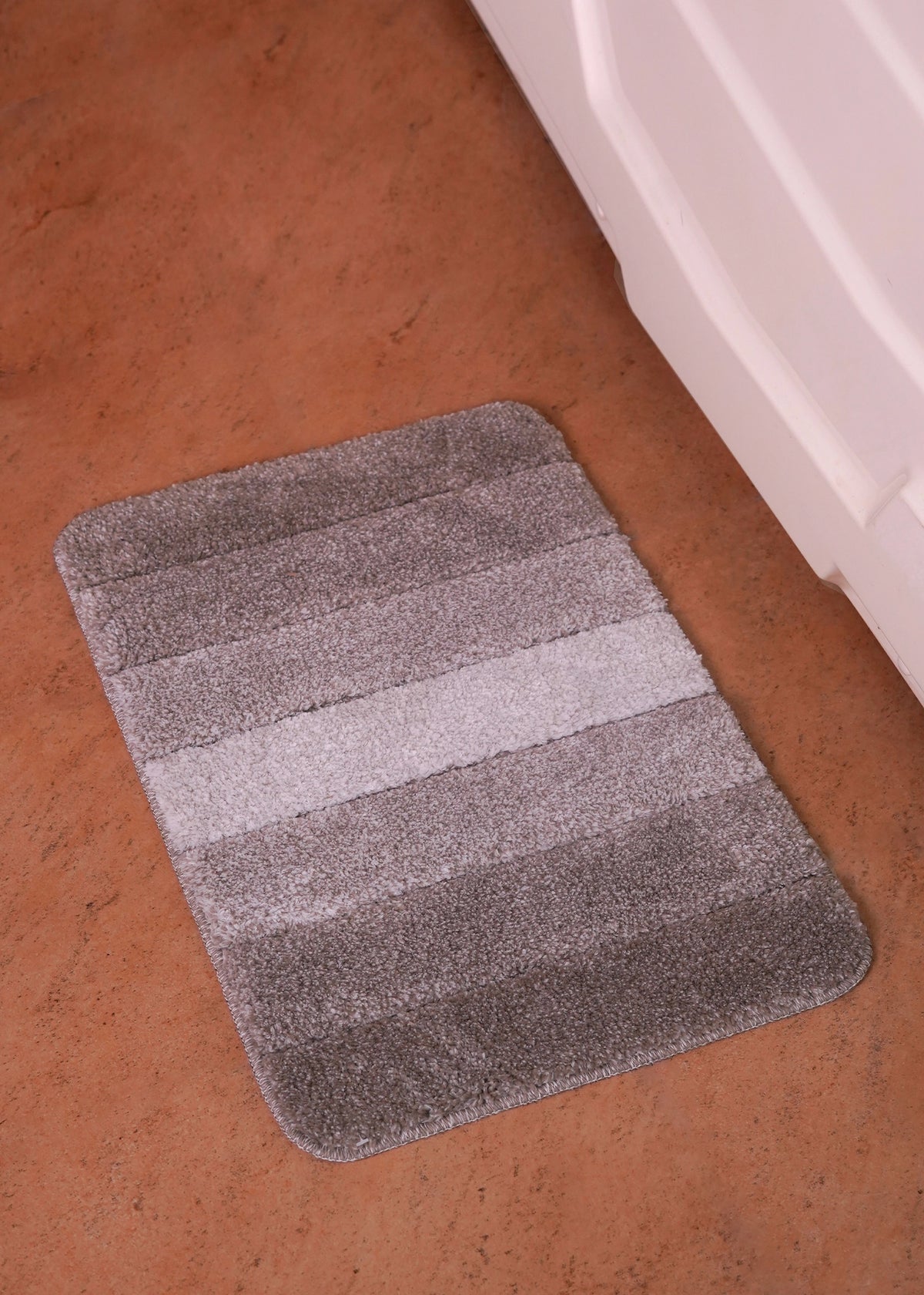 Black bath mat with striped, textured surface and rounded edges