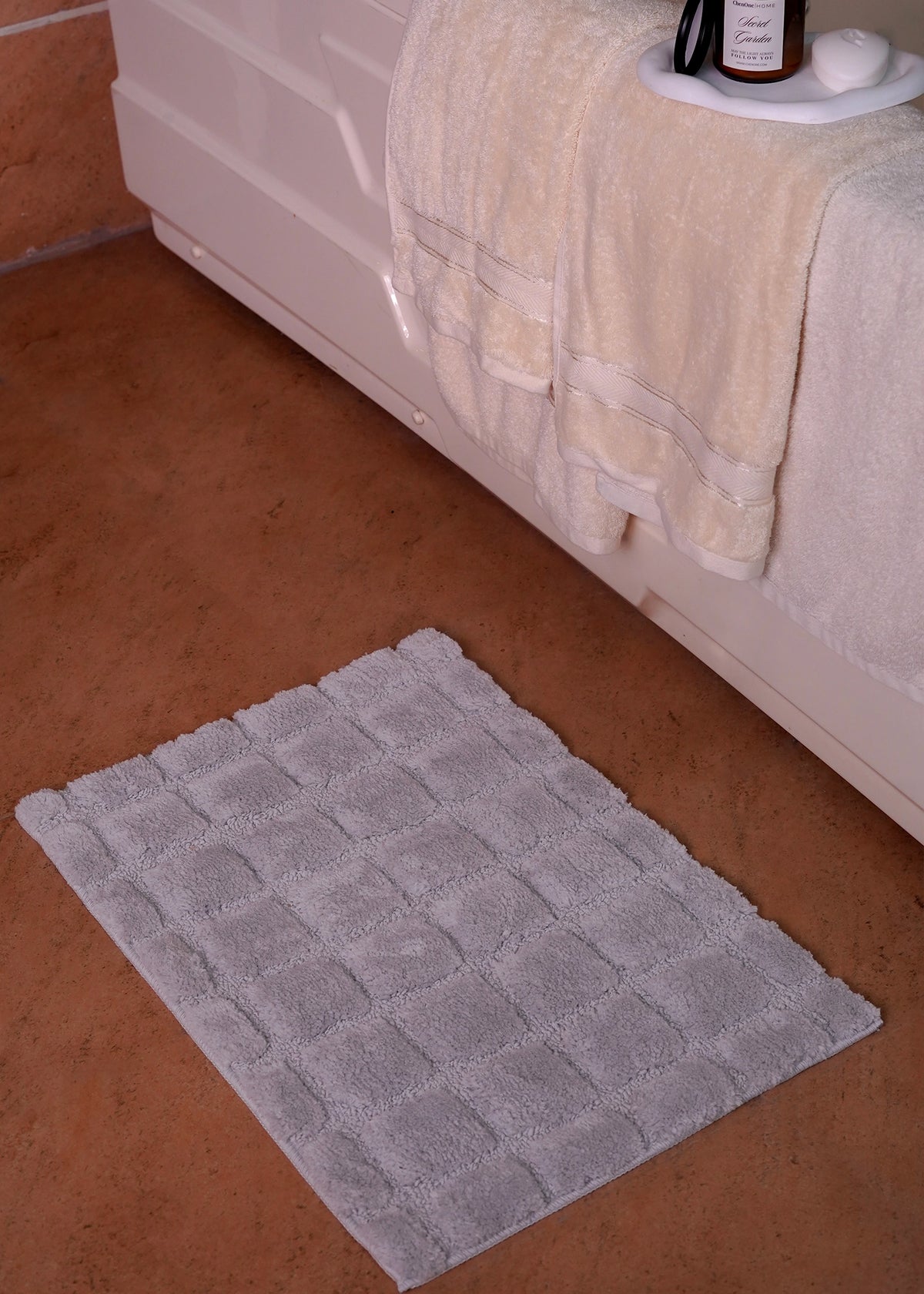 Rectangular grey polyester bath mat with textured surface and grid pattern