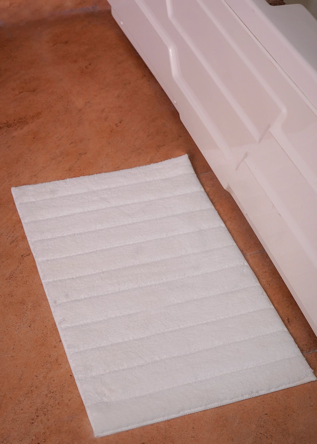 White polyester bath mat with horizontal ribbed pattern, rectangular rug
