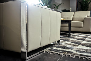 Cream sofa side panel with metal base frame and stitched seat back