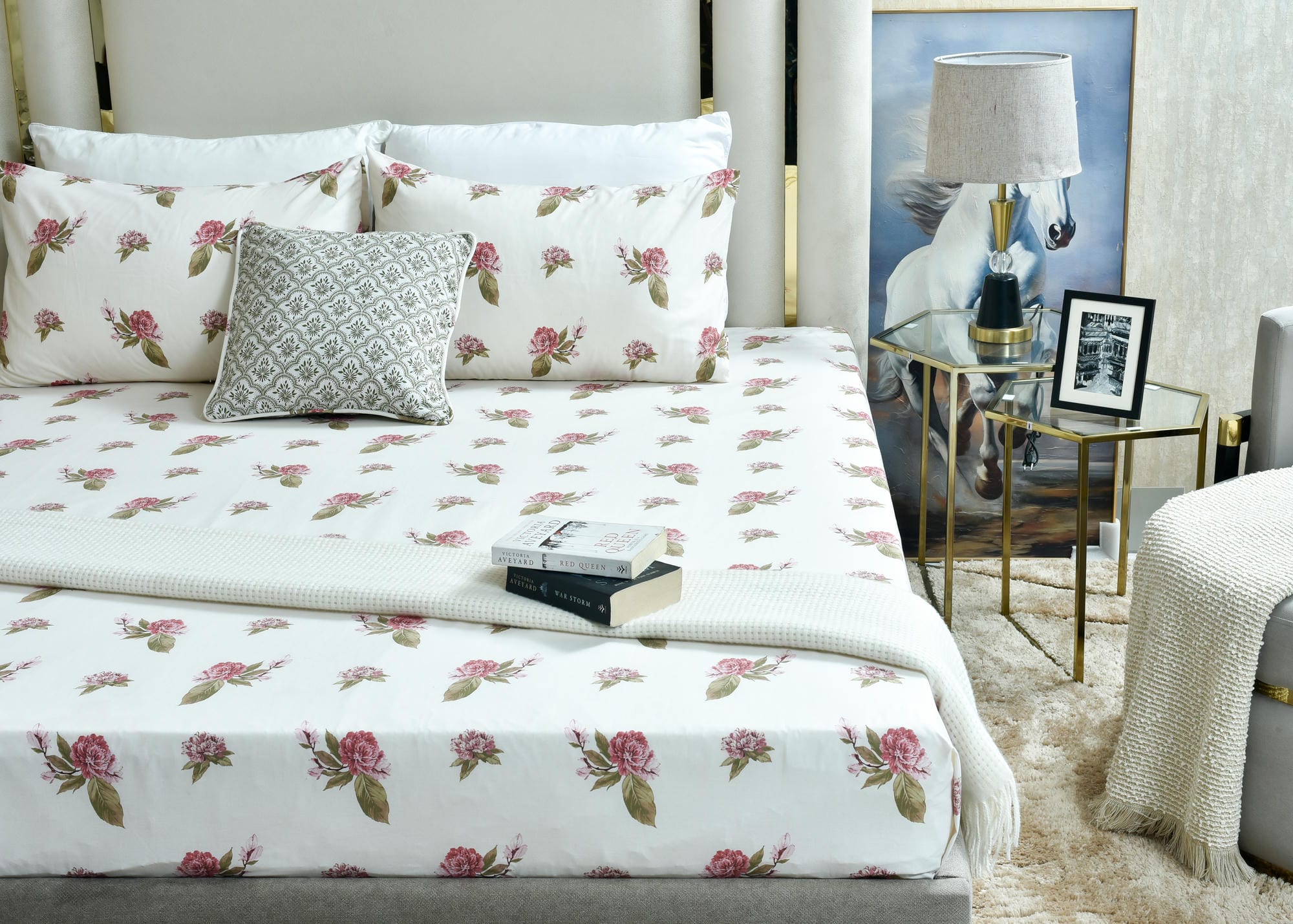 Floral bed sheet with pink roses and green leaves, styled on a made-up bed