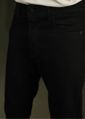 Black chino pants waist close-up: button fly, belt loops, and side pocket detail.