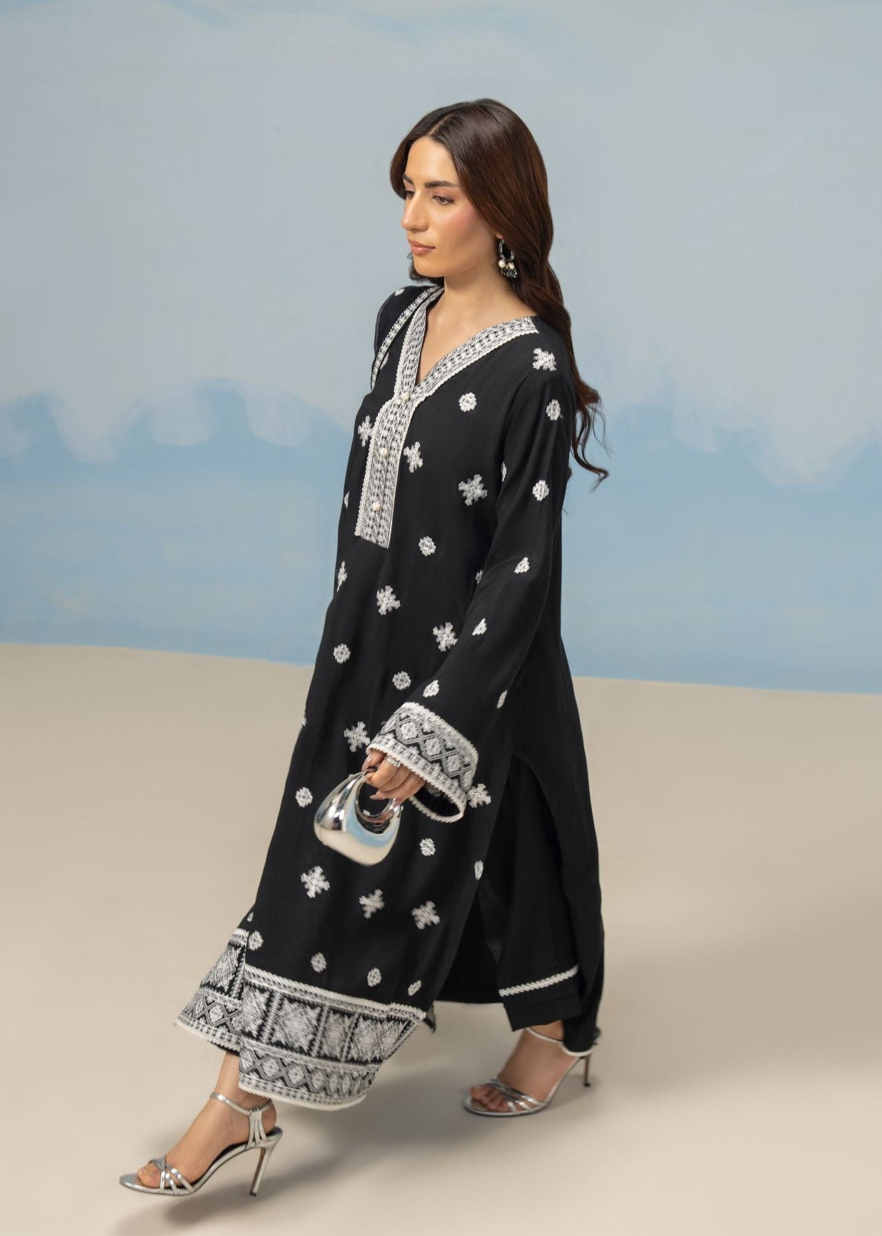 Women's 3-piece black winter suit, side view of long tunic with white motif trim