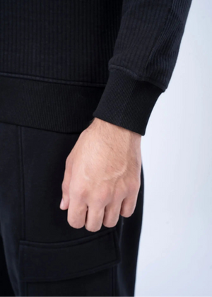 Black waffle-knit sweatshirt cuff and hand, with front pocket detail