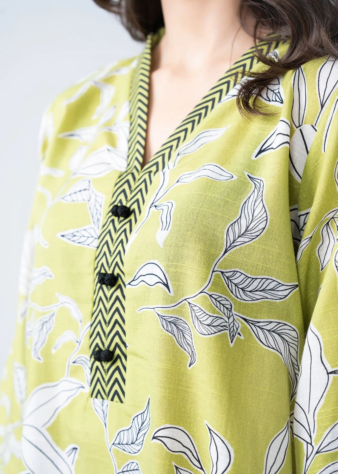 Lime green printed kurta with V-neck placket and black-and-olive trim, close-up