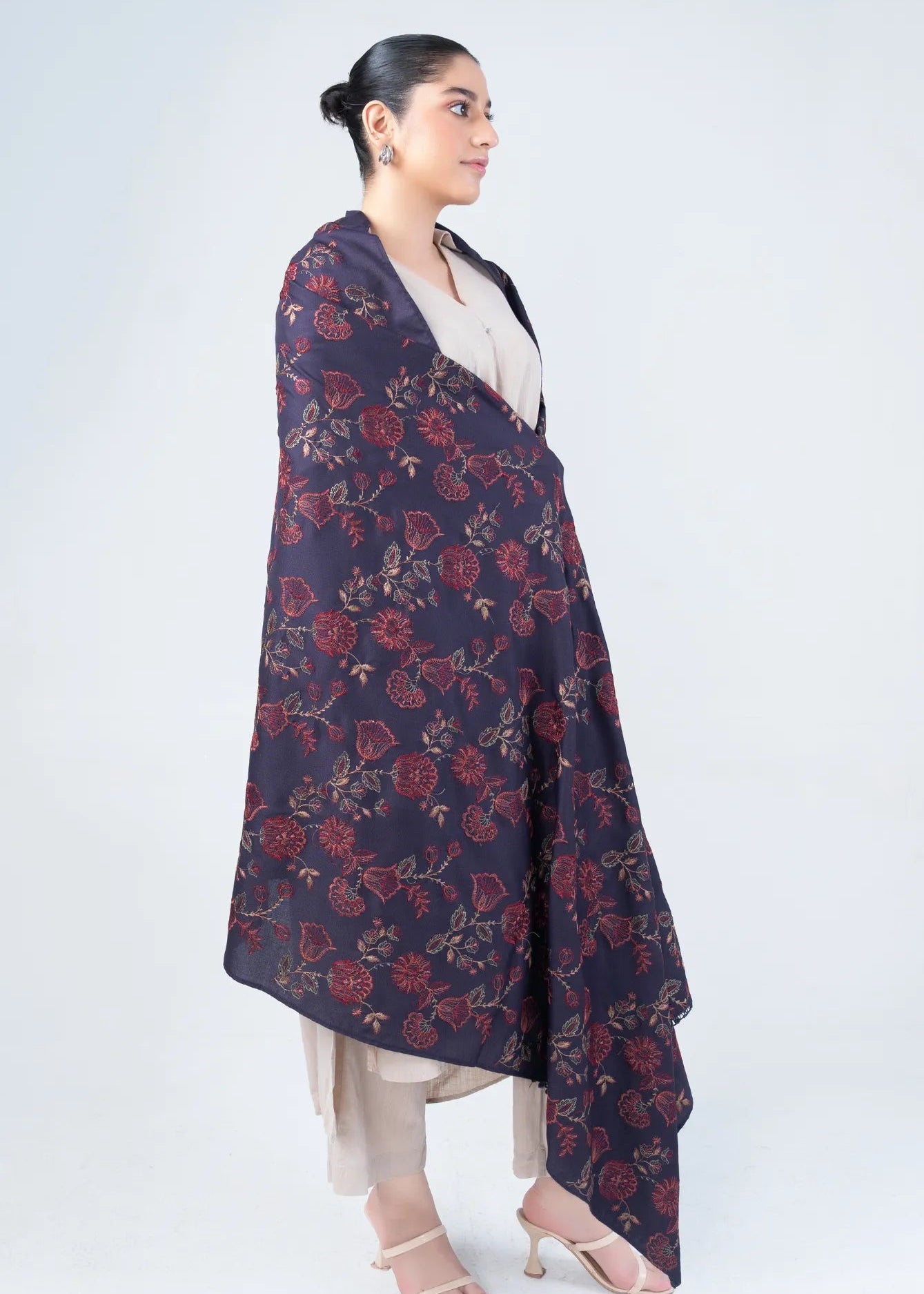 Women's wool winter shawl in dark navy with burgundy floral pattern, worn over beige outfit