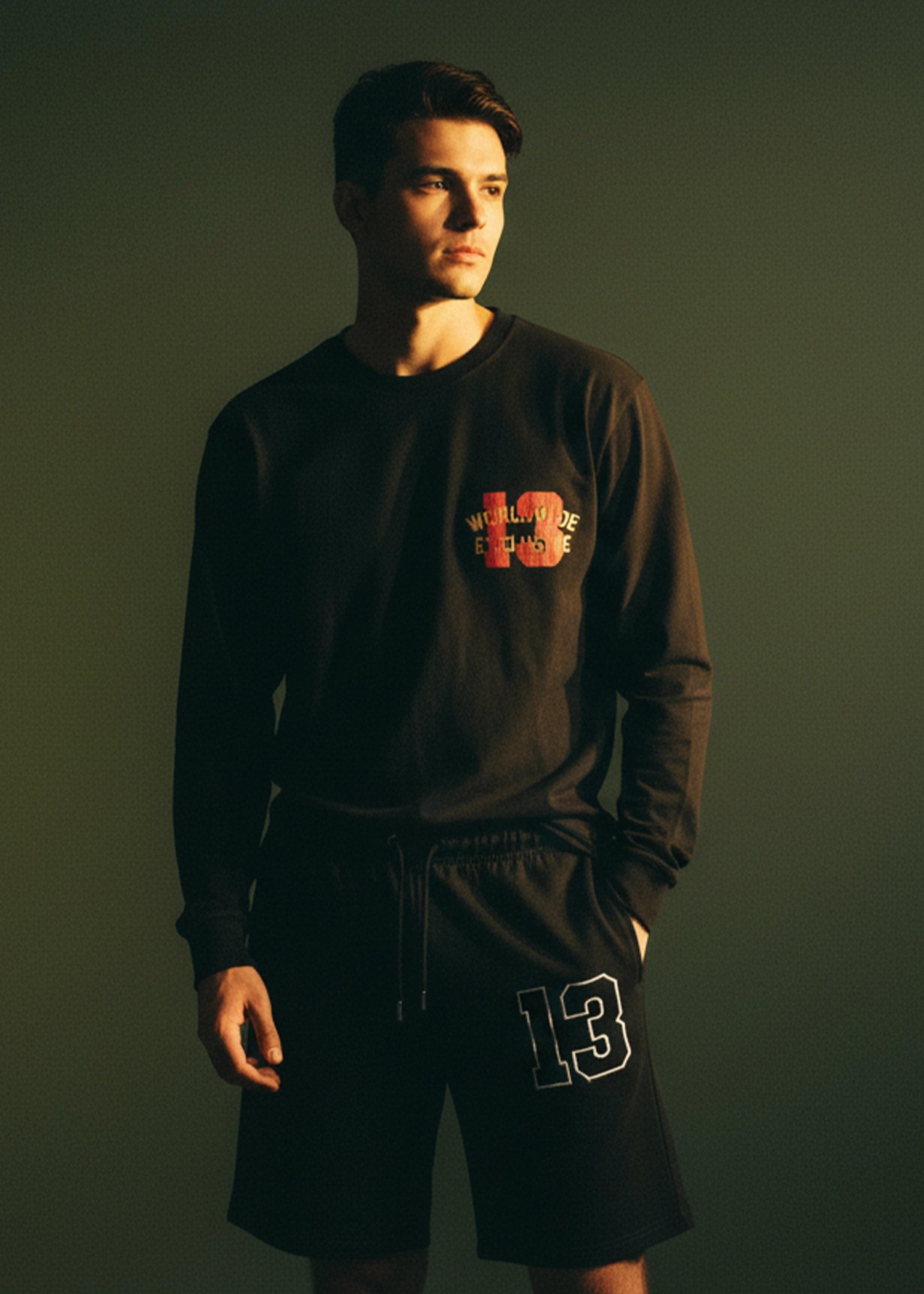 Men's charcoal black long-sleeve crewneck T-shirt with chest graphic logo, side view