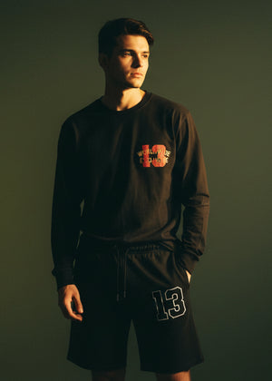 Men's charcoal black long-sleeve crewneck T-shirt with chest graphic logo, side view