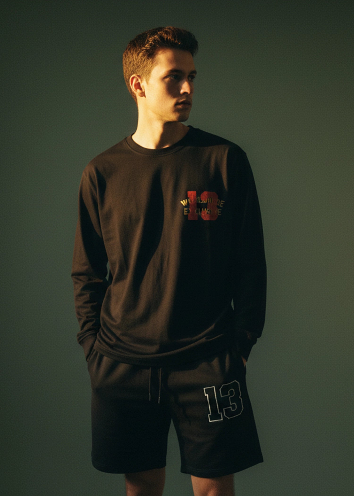 Men's charcoal black long-sleeve crewneck T-shirt with chest graphic logo, 3/4 view