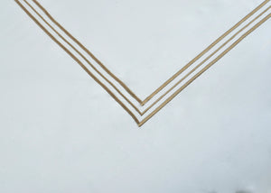 White pillowcase corner with gold double-stripe V border trim