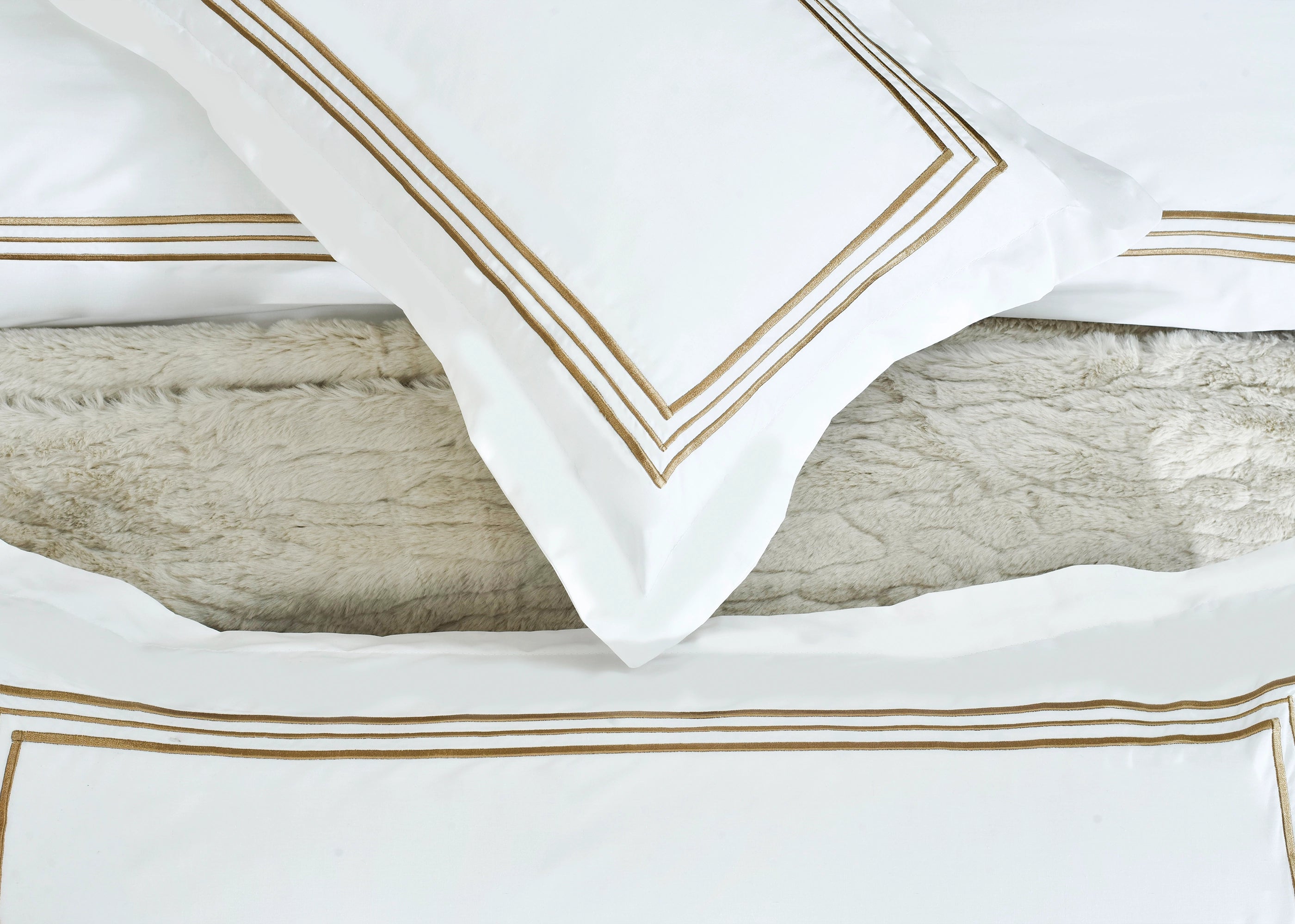 White duvet cover detail with gold-striped frame border and layered bedding