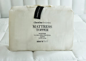 Beige mattress topper cover with hanging label and 'Mattress Topper' text