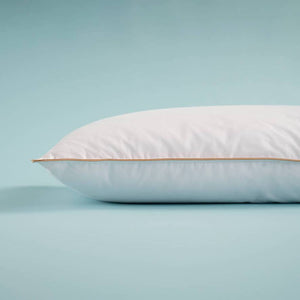 White down-filled pillow with thin orange piping along the edge.