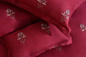 Red comforter fabric with white floral stitching and layered quilting