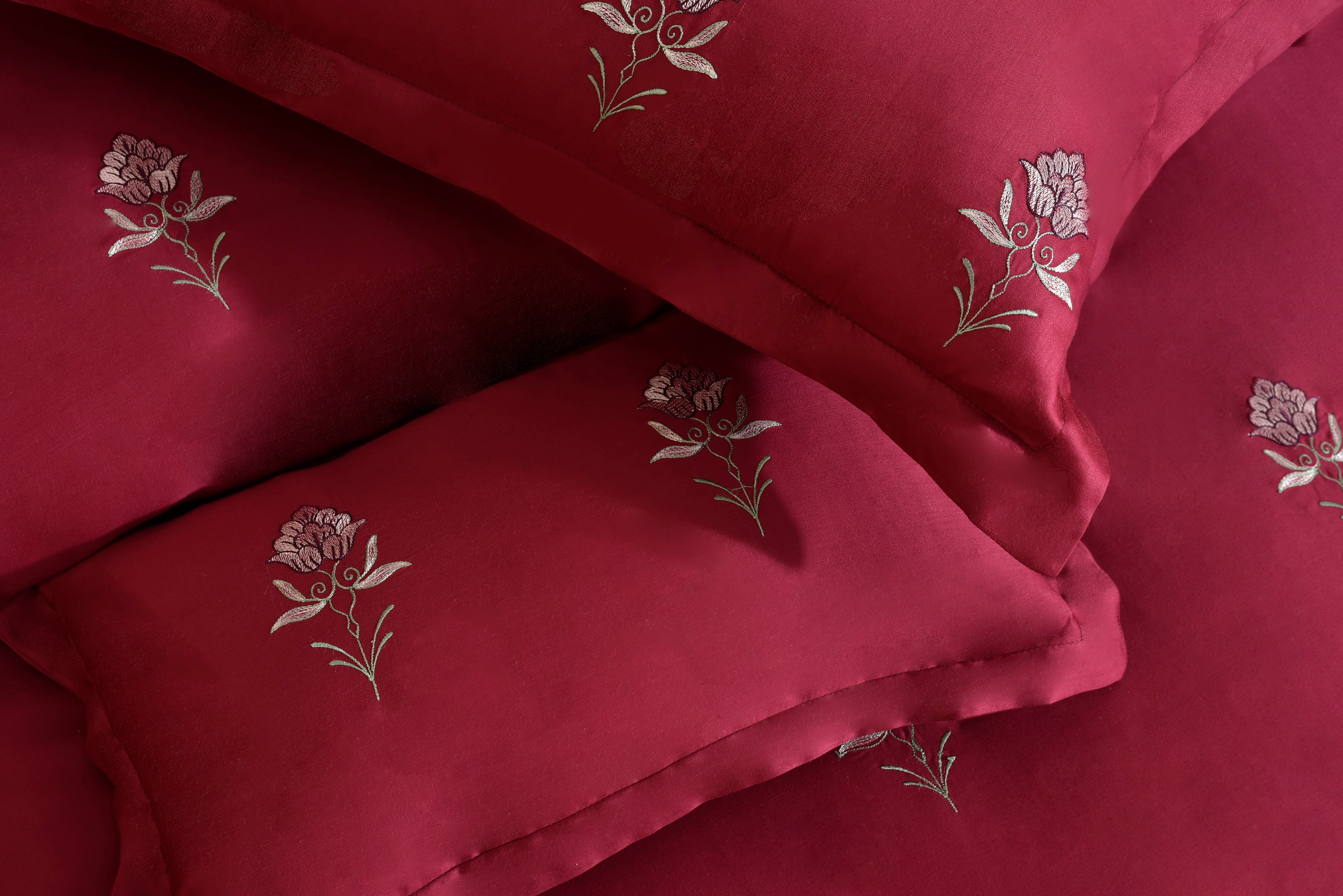 Red comforter fabric with white floral stitching and layered quilting