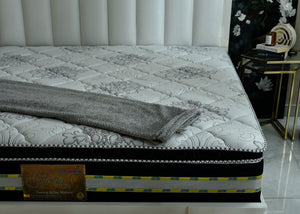 Eurotop spring mattress with white patterned top and folded gray throw