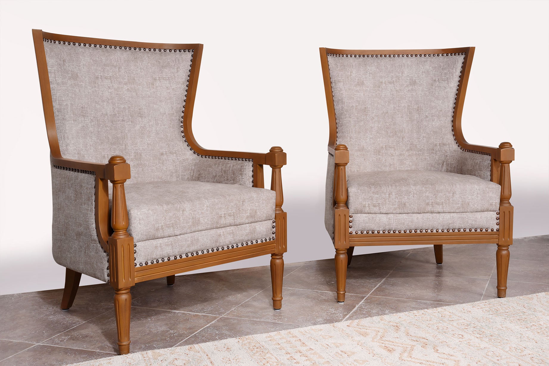 Pair of Koko room chairs with light gray upholstered arms and carved wooden legs