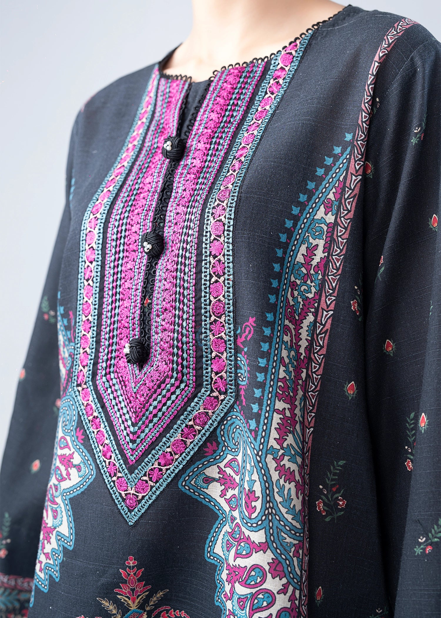 Close-up of dark kurta neckline with magenta and teal embroidery, tassel trim