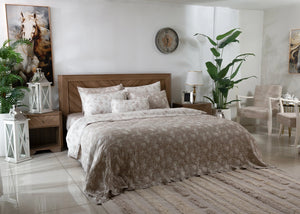 Beige textured coverlet set with quilt and multiple pillows on bed, with matching shams