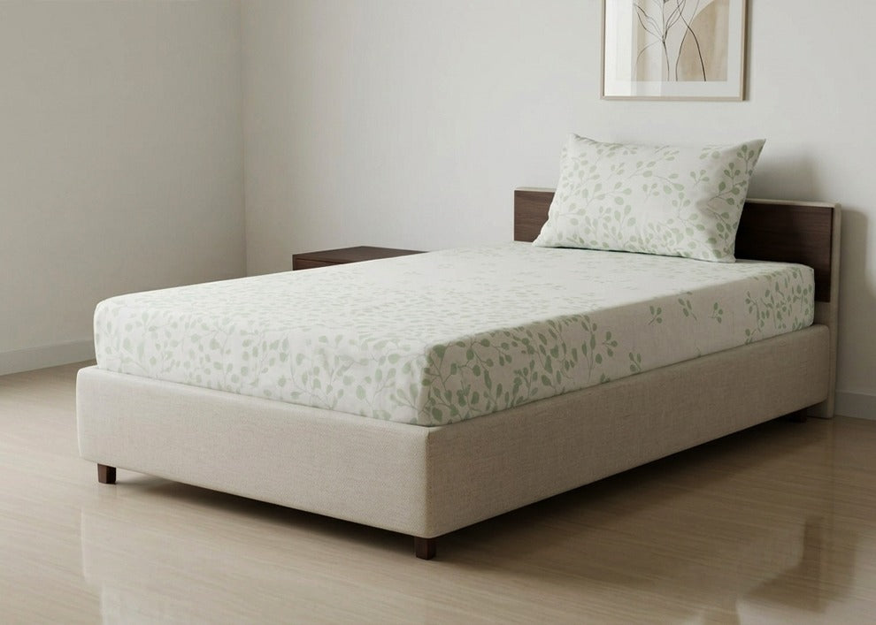 Cotton bed sheet set with light green floral pattern, neatly fitted on a bed