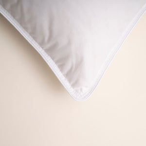 White down-filled pillow with stitched corner and smooth fabric cover