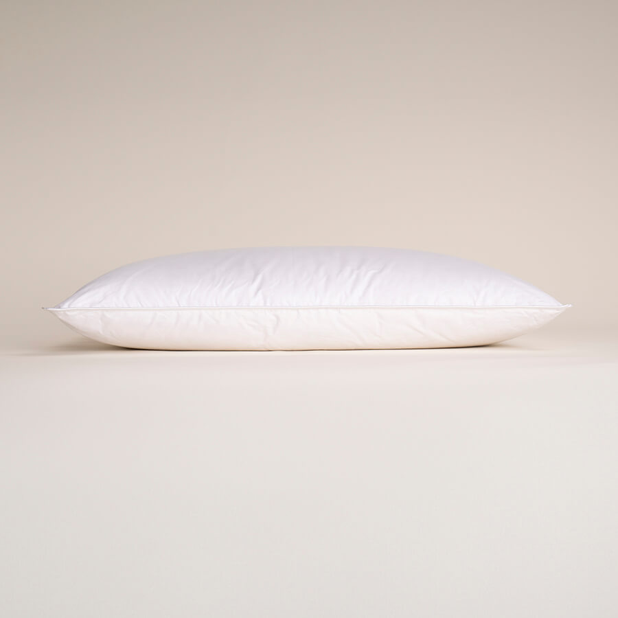White soft-filled pillow lying horizontally with smooth fabric cover