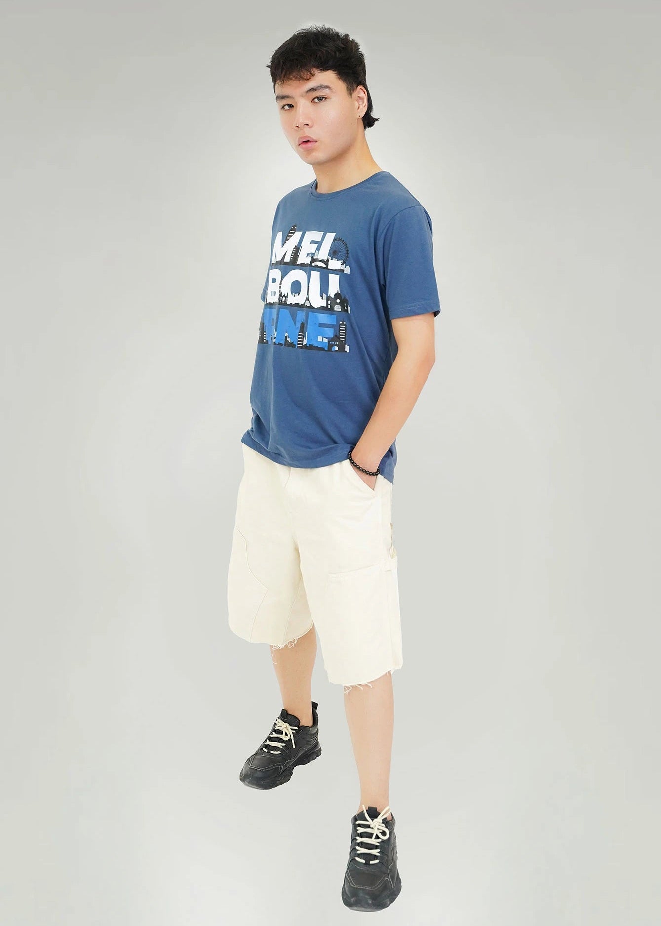 Men's navy round-neck T-shirt with city skyline graphic, worn with cream shorts
