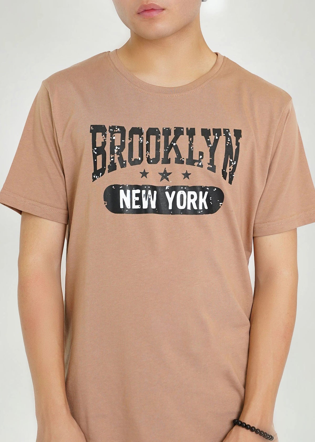 Men's brown round-neck T-shirt close-up of BROOKLYN NEW YORK graphic